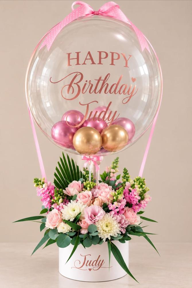 Personalised pink and gold printed bubble balloon rising from a fresh rose and chrysanthemum arrangement in a named white hat box