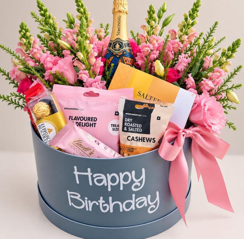 Blue-grey Happy Birthday hat box with Cap Classique, pink snapdragons and gourmet chocolates finished with a satin bow