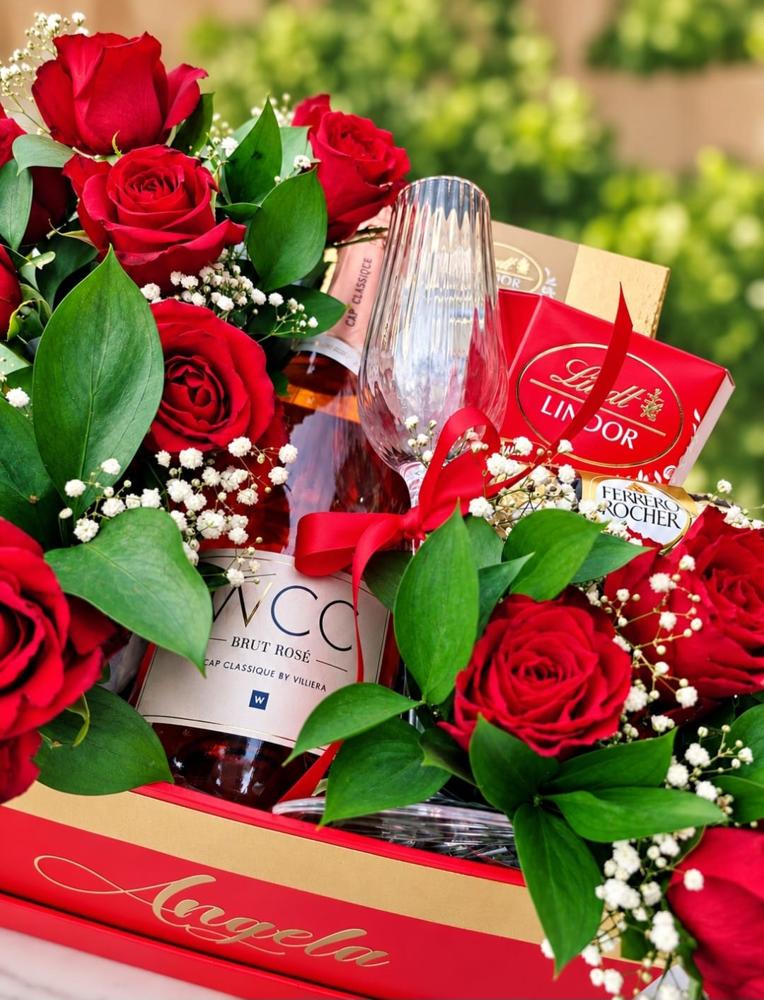 Red roses, Cap Classique sparkling wine, a crystal flute and Lindt and Ferrero chocolates arranged in a personalised red gift box