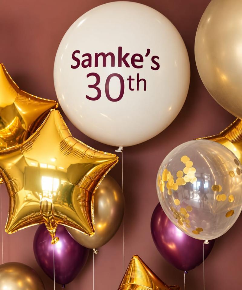 Close-up of a custom-printed 30th birthday jumbo balloon with gold star balloons, burgundy chrome and gold confetti balloons