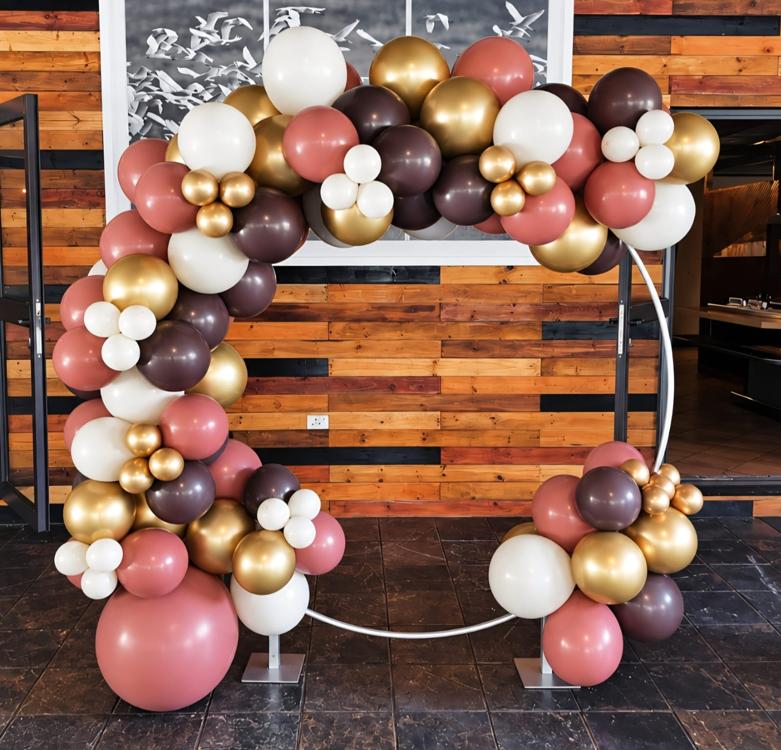 Round balloon arch in dusty rose, chocolate, cream and chrome gold on a hoop frame at a restaurant venue