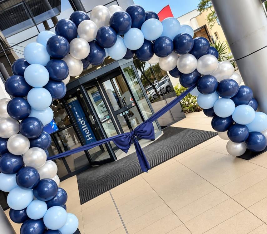 Navy, pale blue and silver balloon arch with a satin bow across a corporate office entrance