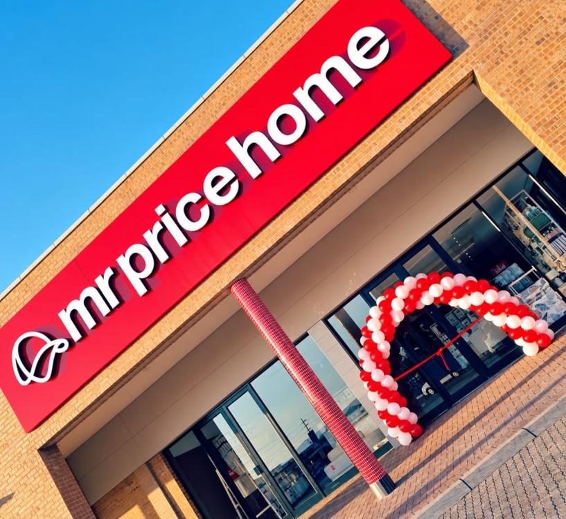 Red and white spiral balloon arch with a ribbon-cutting line at a new store entrance on opening day